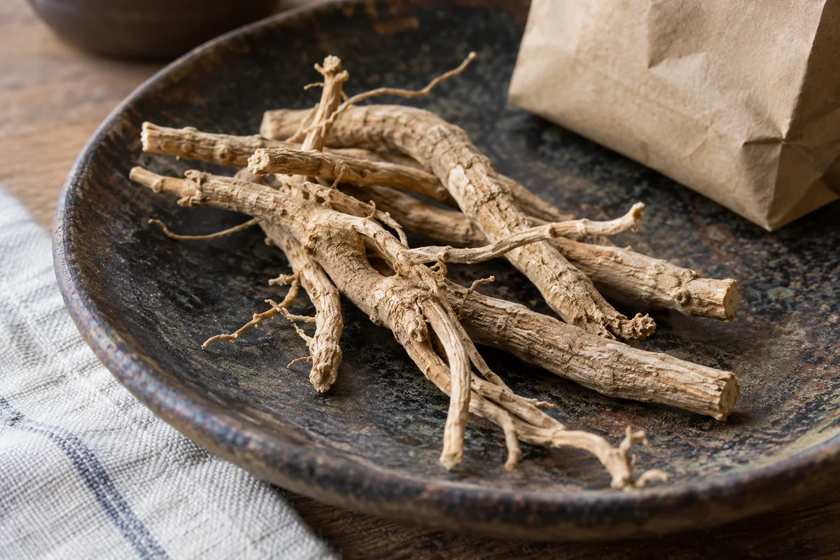 Kuivattuja ashwagandhan juuria tummalla keraamisella lautasella.
